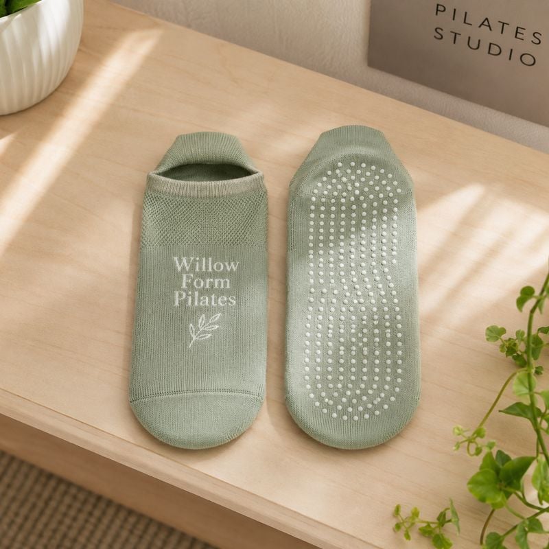 Custom full-toe pilates grip socks in sage green with a knit studio logo and silicone grip sole