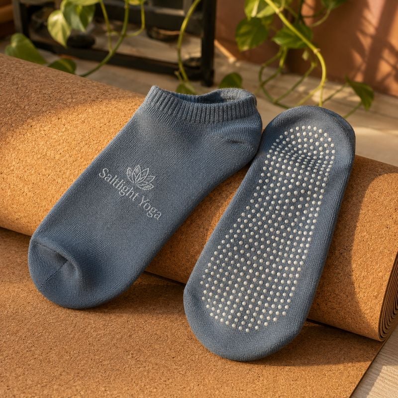 Custom grip socks for yoga studios resting on a rolled cork yoga mat